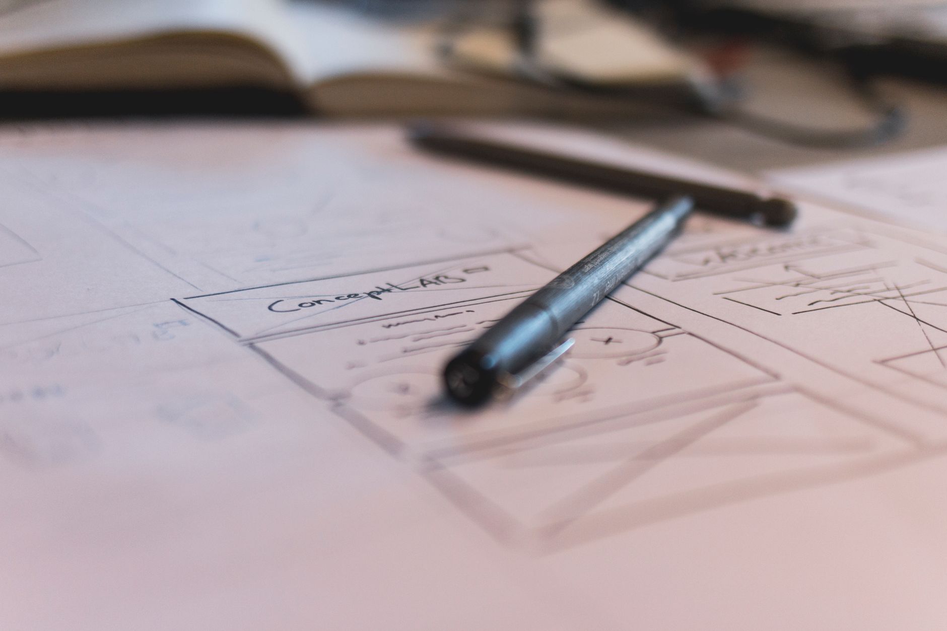 Hand-drawn storyboard frames pinned to a wooden desk next to a pencil