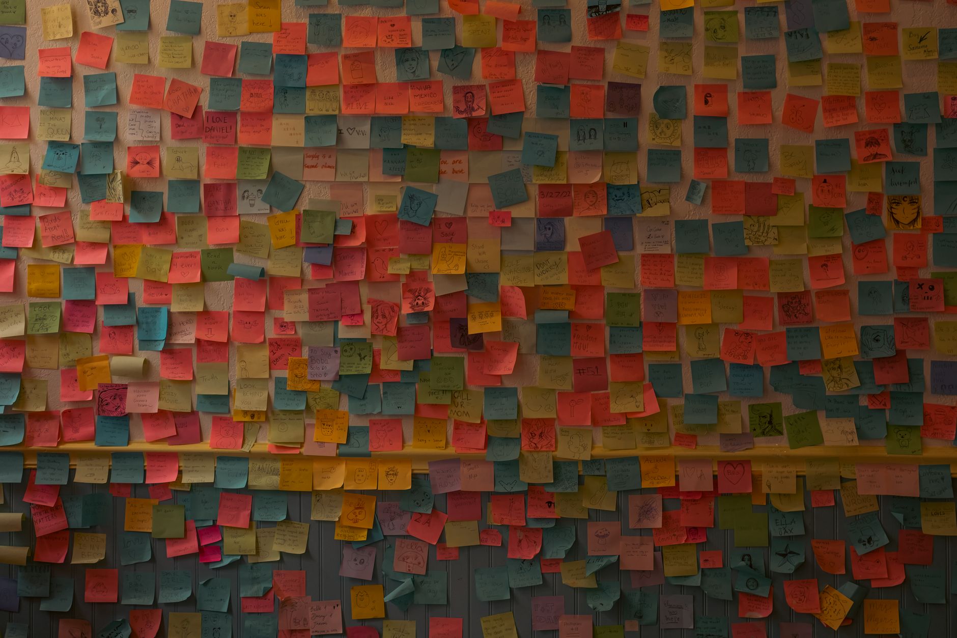 Rows of handwritten sticky notes arranged on a studio wall