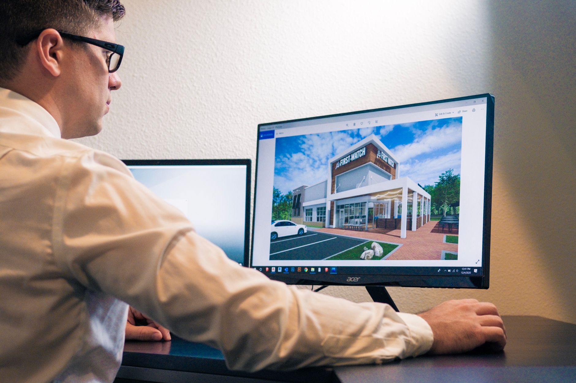A small creative team gathered around a large screen showing a 3D interior design