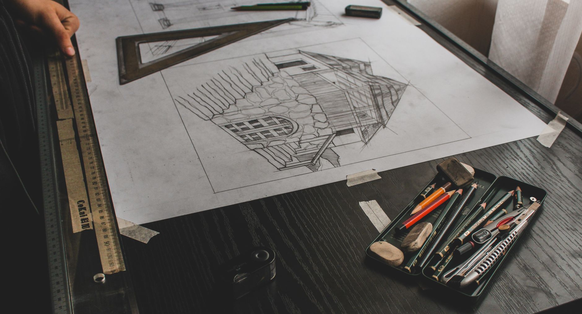Hand-drawn floor plan sketches and a pencil on a drafting desk