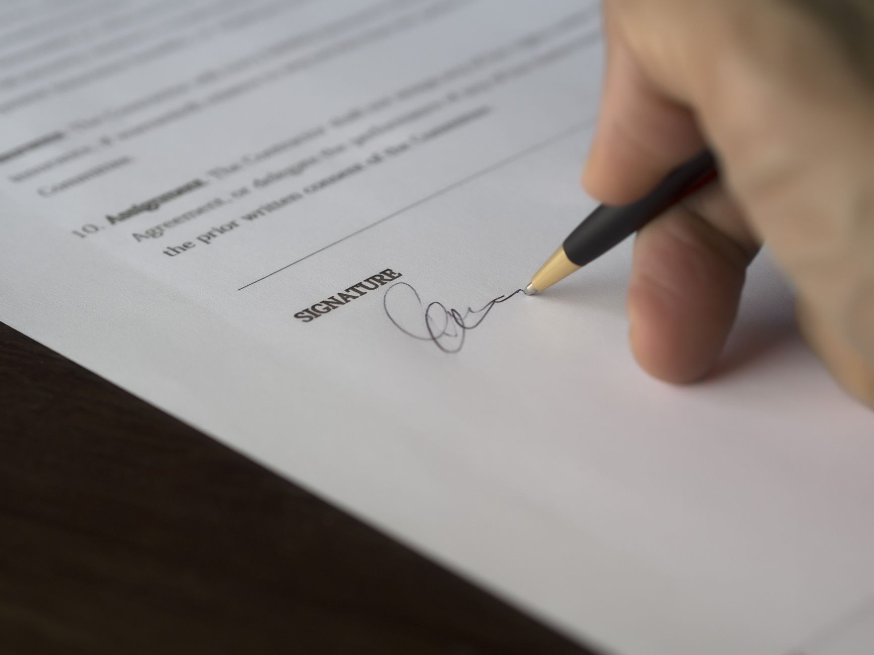 A pen resting on a signature line of a printed agreement