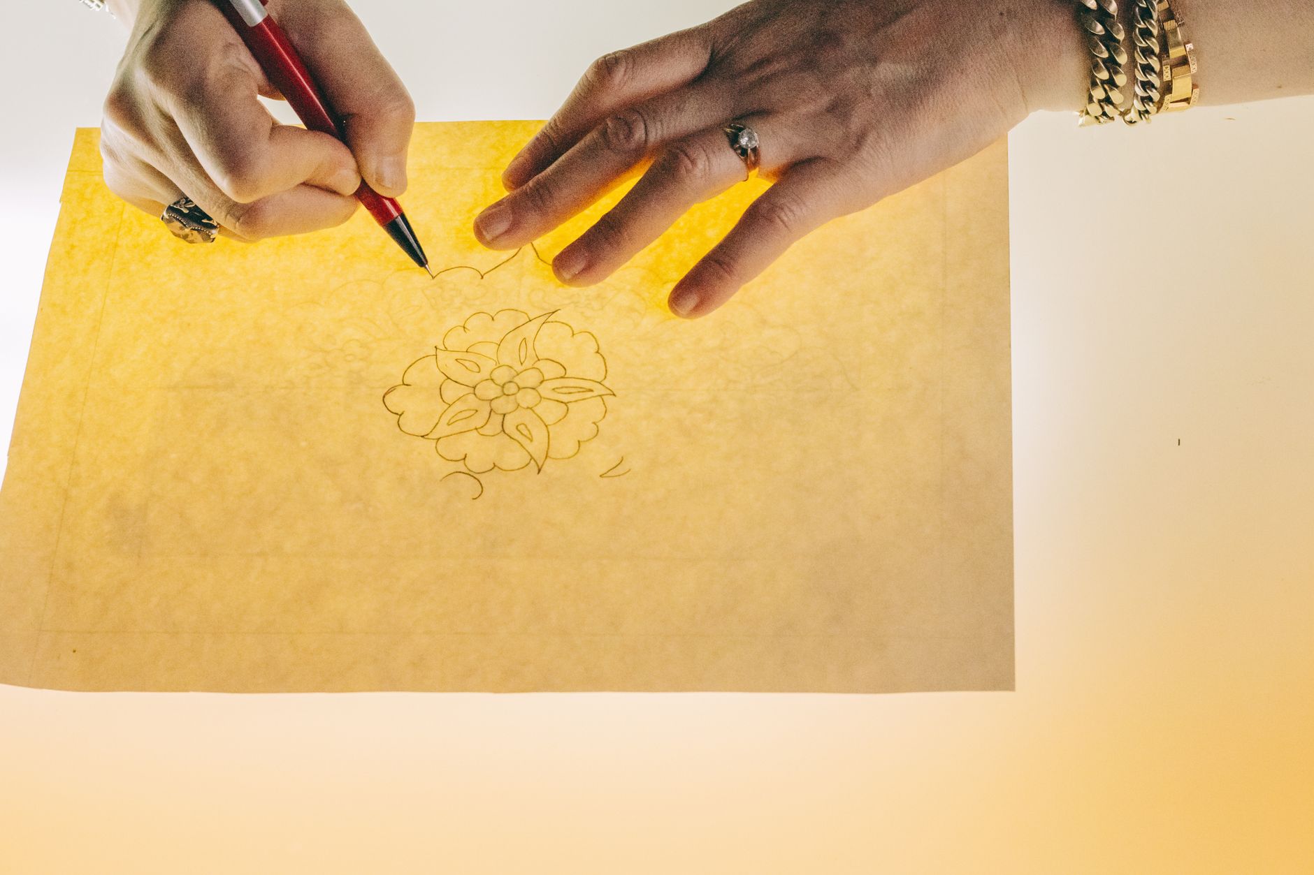 Pencil logo sketches on layered tracing paper on a desk