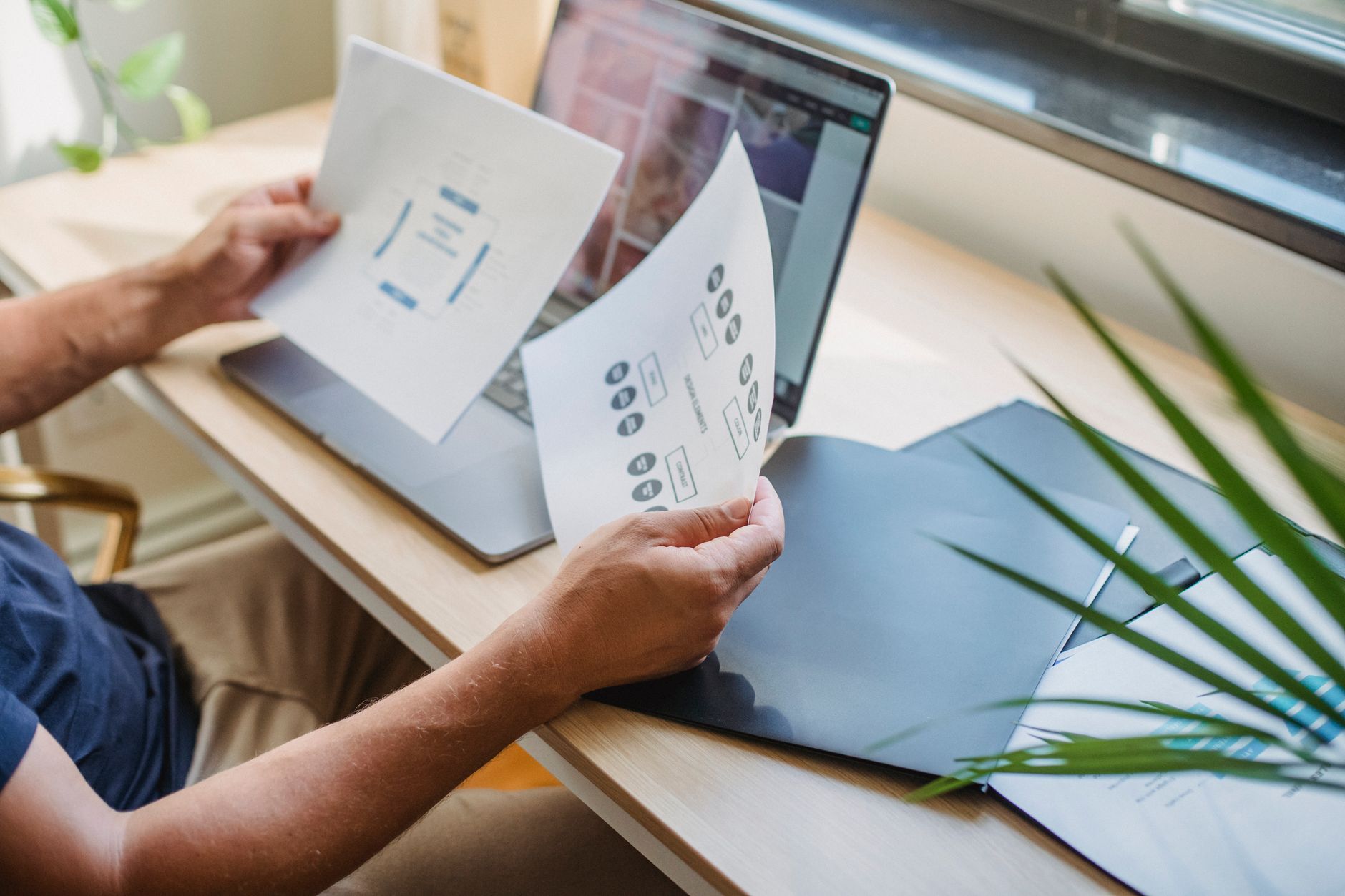 A designer arranging a brand identity proposal on a laptop in a studio