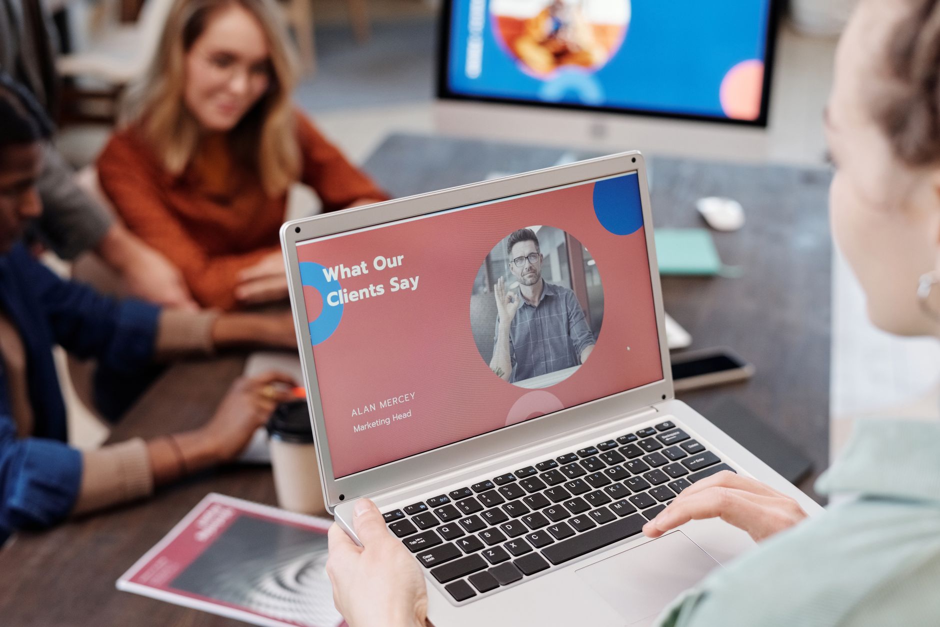 A laptop on a meeting table showing a proposal page next to printed packaging mockups