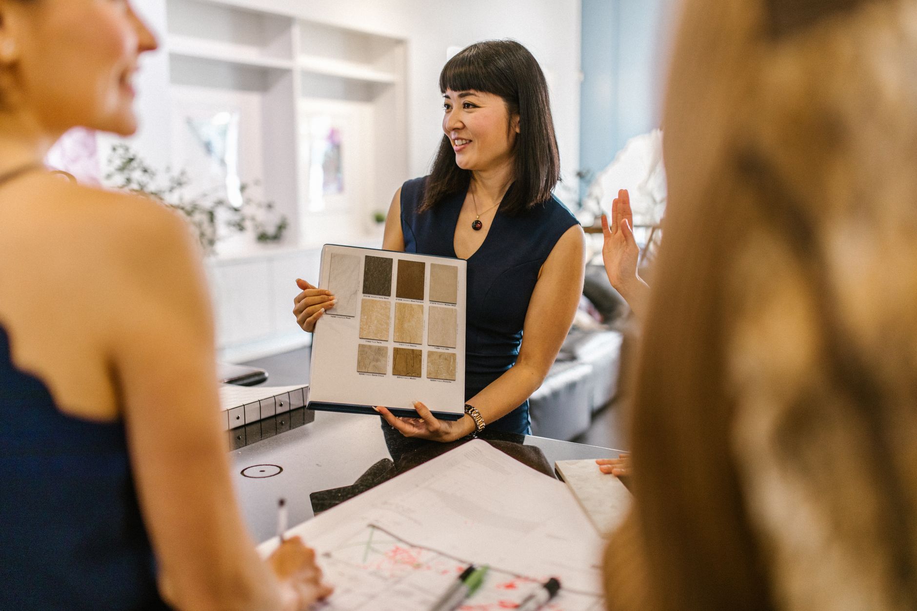 A designer points at printed brand concepts spread across a meeting table