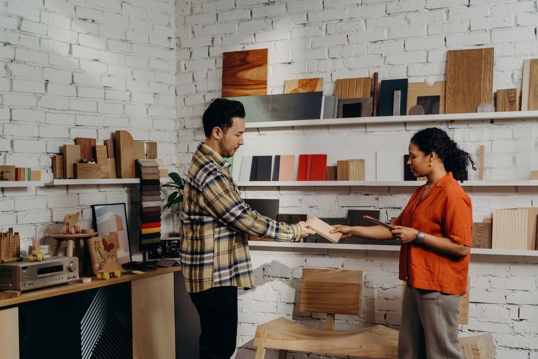 A designer walks a client through printed layouts on a studio table