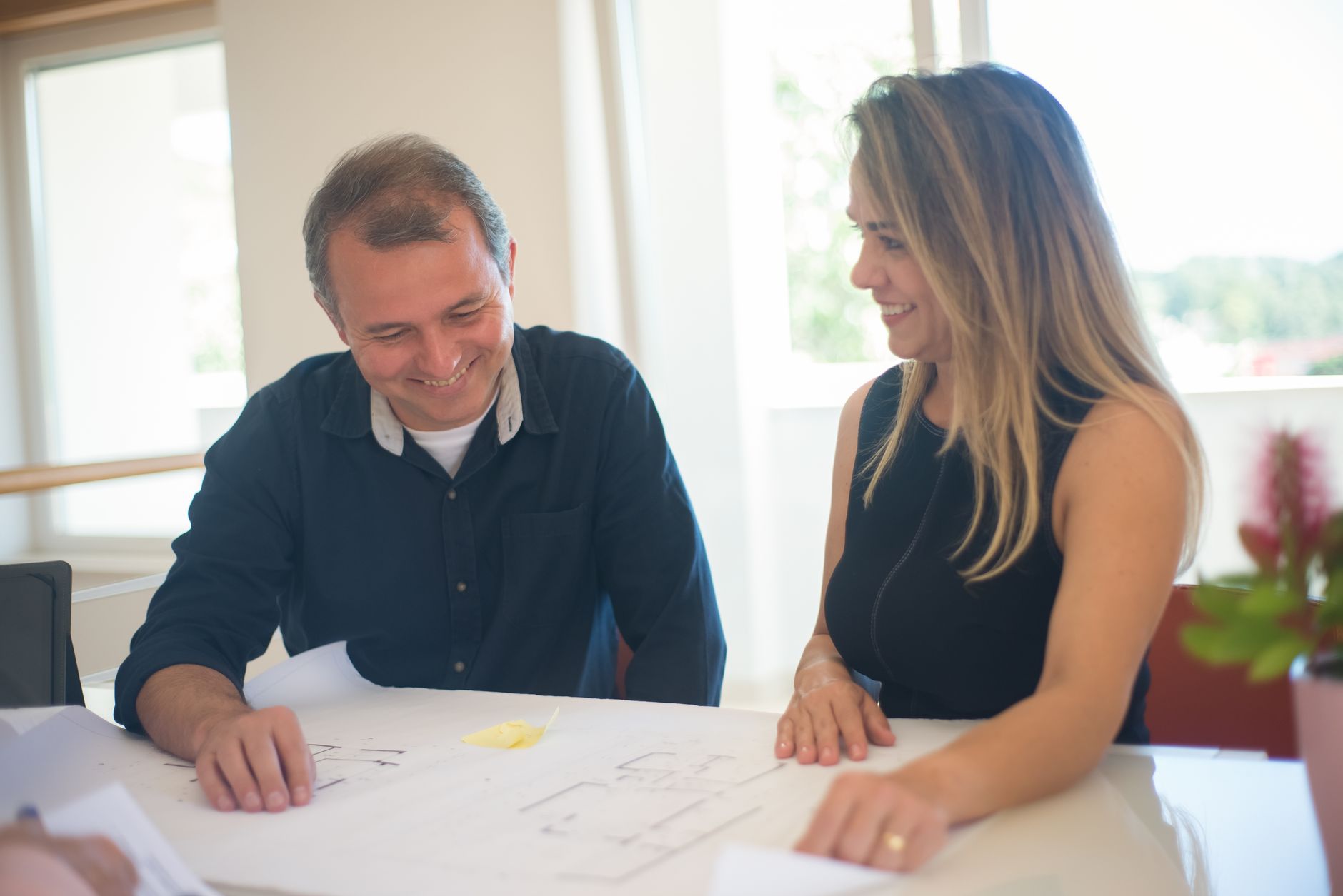 A designer and a client reviewing printed brand concepts across a studio table