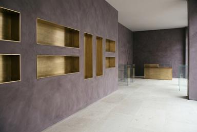 Boutique interior in violet plaster, brass and pale stone