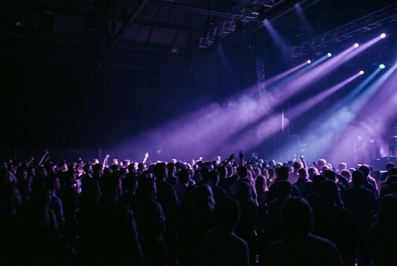 Crowd silhouetted against a violet stage wash